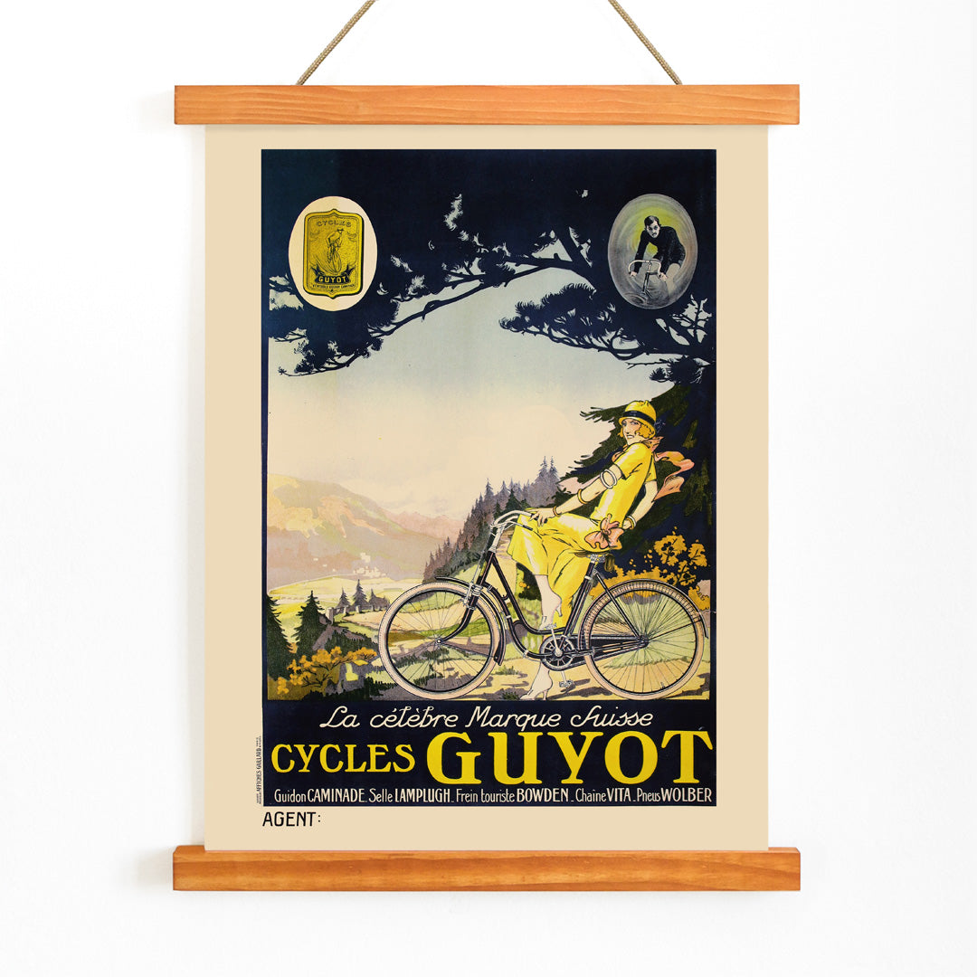 Woman in yellow riding a bicycle through a scenic landscape Cycles Guyot vintage poster artwork, with wooden magnetic frame on white background