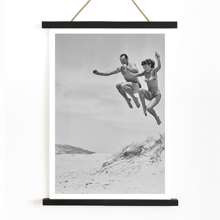 Two Tivoli Stars performing an acrobatic jump on a sandy beach in swimsuits Acrobatics at the Beach poster, with wooden magnetic frame on white background