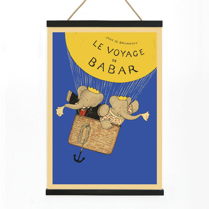 Le Voyage de Babar by Jean de Brunhoff illustration and poster featuring elephants in a hot air balloon with a yellow balloon on a blue background, with wooden magnetic frame on white background
