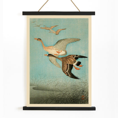 Flying Geese by Ohara Koson Japanese woodblock print poster with two geese flying over water and reeds artwork wall art print, with wooden magnetic frame on white background
