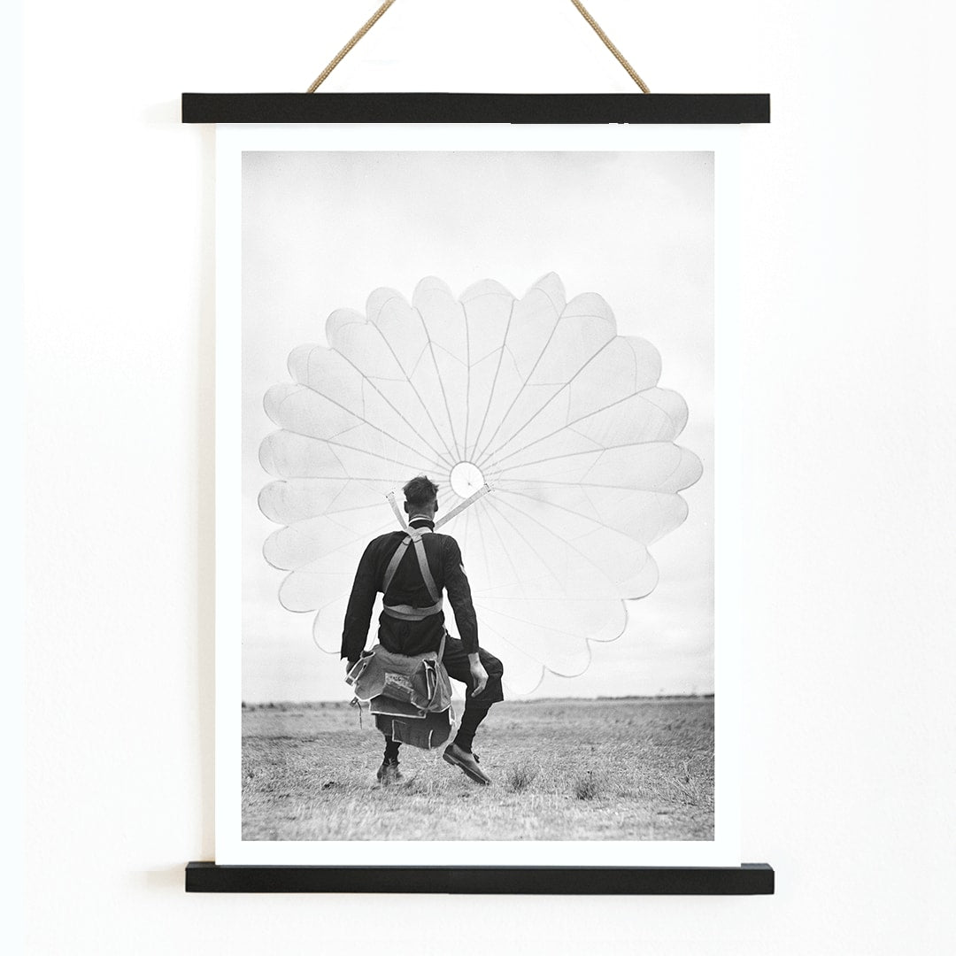 Air force parachuter landing and standing with deployed parachute by Ray Olsen poster, with wooden magnetic frame on white background