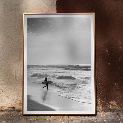 Black and white poster of a surfer with a board entering the ocean titled Surfer in Portugal by artist Black, framed and displayed in home decor