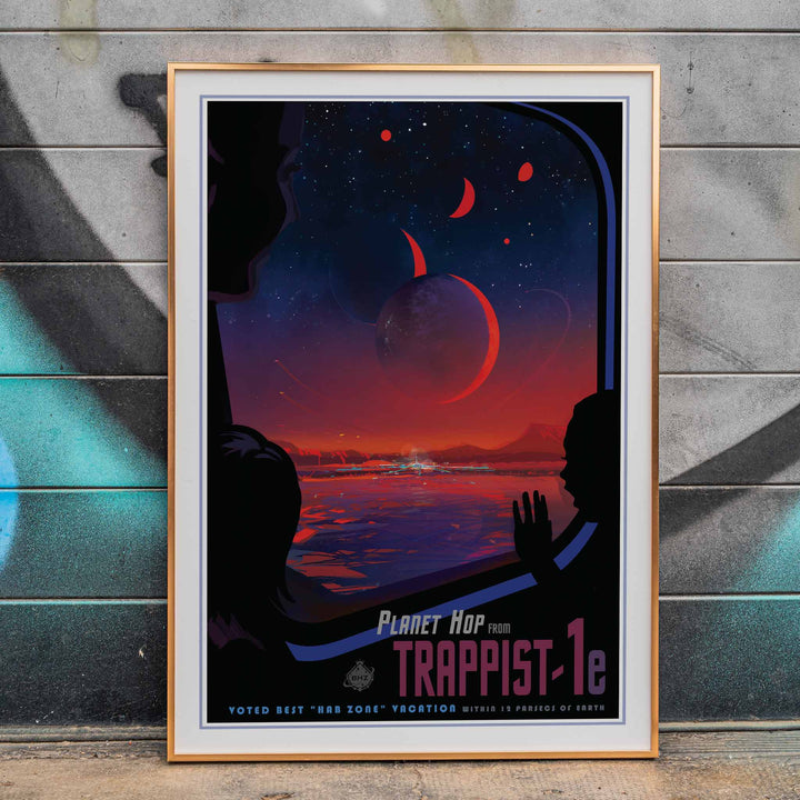 Colorful sci fi poster of TRAPPIST-1e by NASA showing vibrant alien landscape with planets glowing sky and silhouetted figures viewed from a window, framed and displayed in home decor