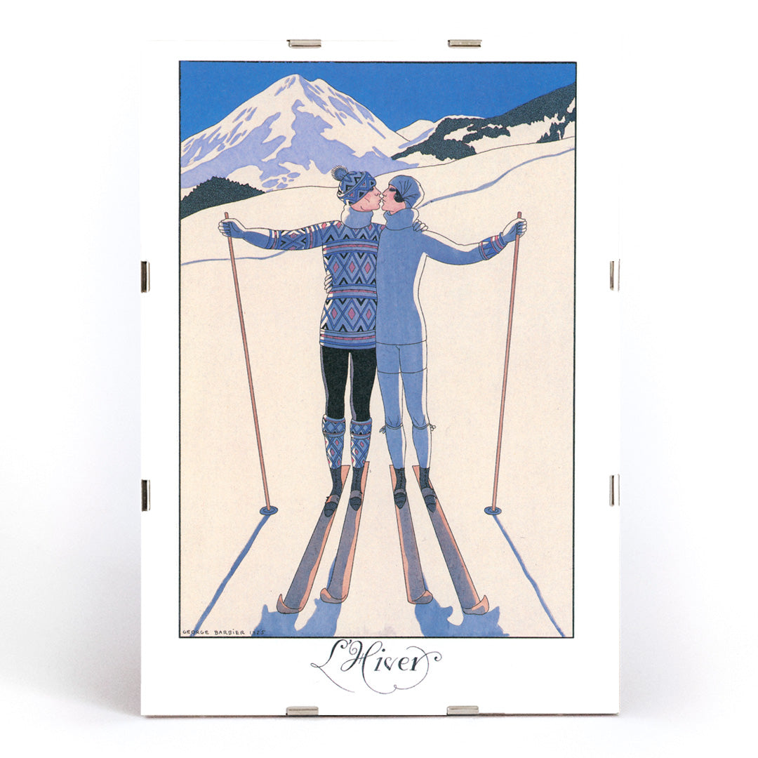 Two skiers kissing in snowy mountain landscape L Hiver by George Barbier vintage poster artwork, framed and displayed in modern living room decor