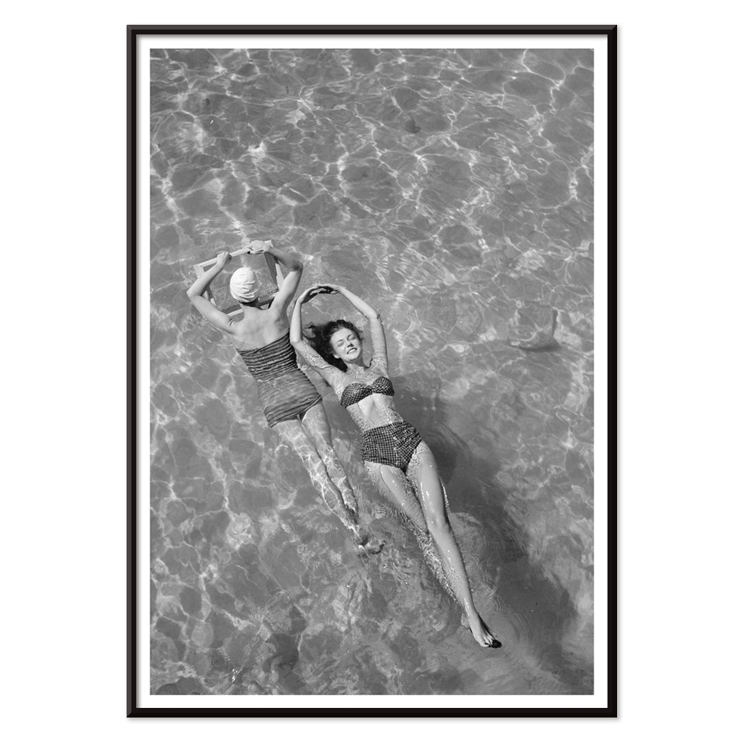 Fashion models in vintage bathing suits floating in a swimming pool artwork by Toni Frissell, with black aluminium frame on white background