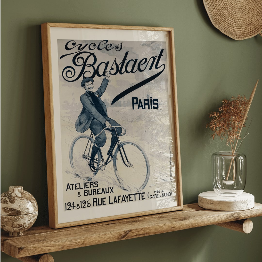 Vintage bicycle poster joyful man riding and waving on Cycles Bastaent Paris bike artwork by Charles Tichon, framed and displayed in home decor